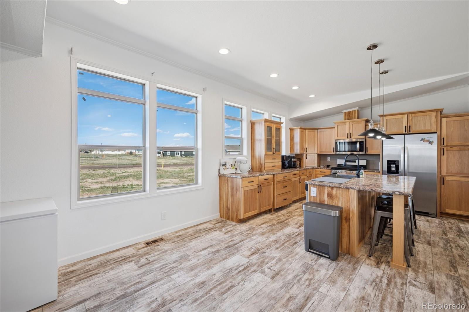 311 Silver Street Hugo, CO 80821 - Photo 19 of 33 a kitchen with stainless steel appliances kitchen island granite countertop a stove a sink a refrigerator and white cabinets with wooden floor