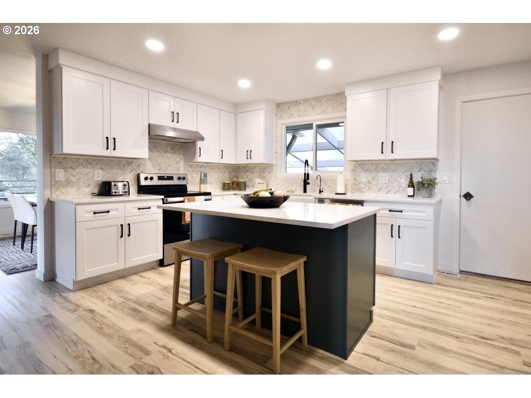 10854 Summit Loop Road Southeast Turner, OR 97392 - Photo 11 of 35 a kitchen with stainless steel appliances kitchen island granite countertop a sink cabinets and wooden floor