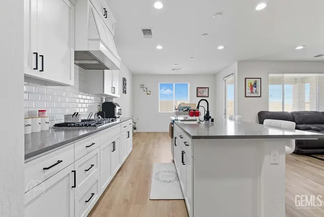 a large white kitchen with stainless steel appliances granite countertop a sink and cabinets
