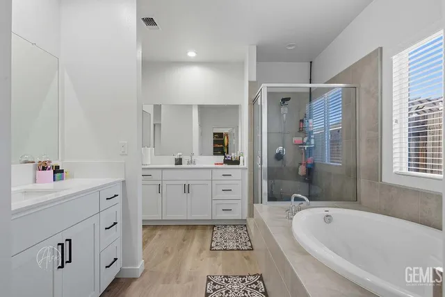 a bathroom with a tub sink double vanity granite and a bathtub