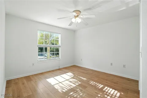 an empty room with chandelier fan and windows