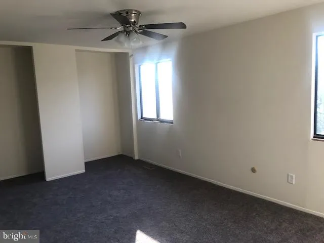 an empty room with a window and a fan