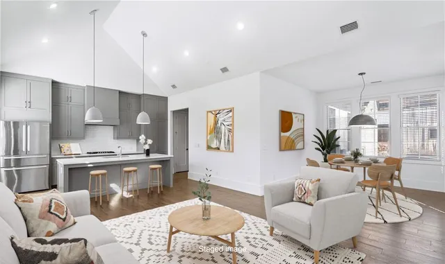 a living room with stainless steel appliances kitchen island granite countertop furniture and a wooden floor