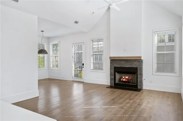 a view of an empty room with wooden floor fireplace and a window