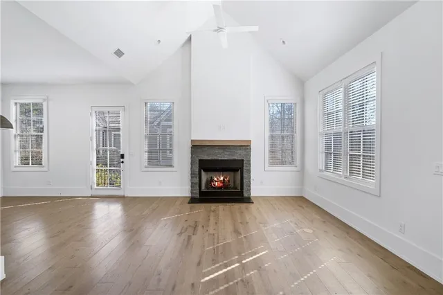 a view of an empty room with wooden floor fireplace and a window