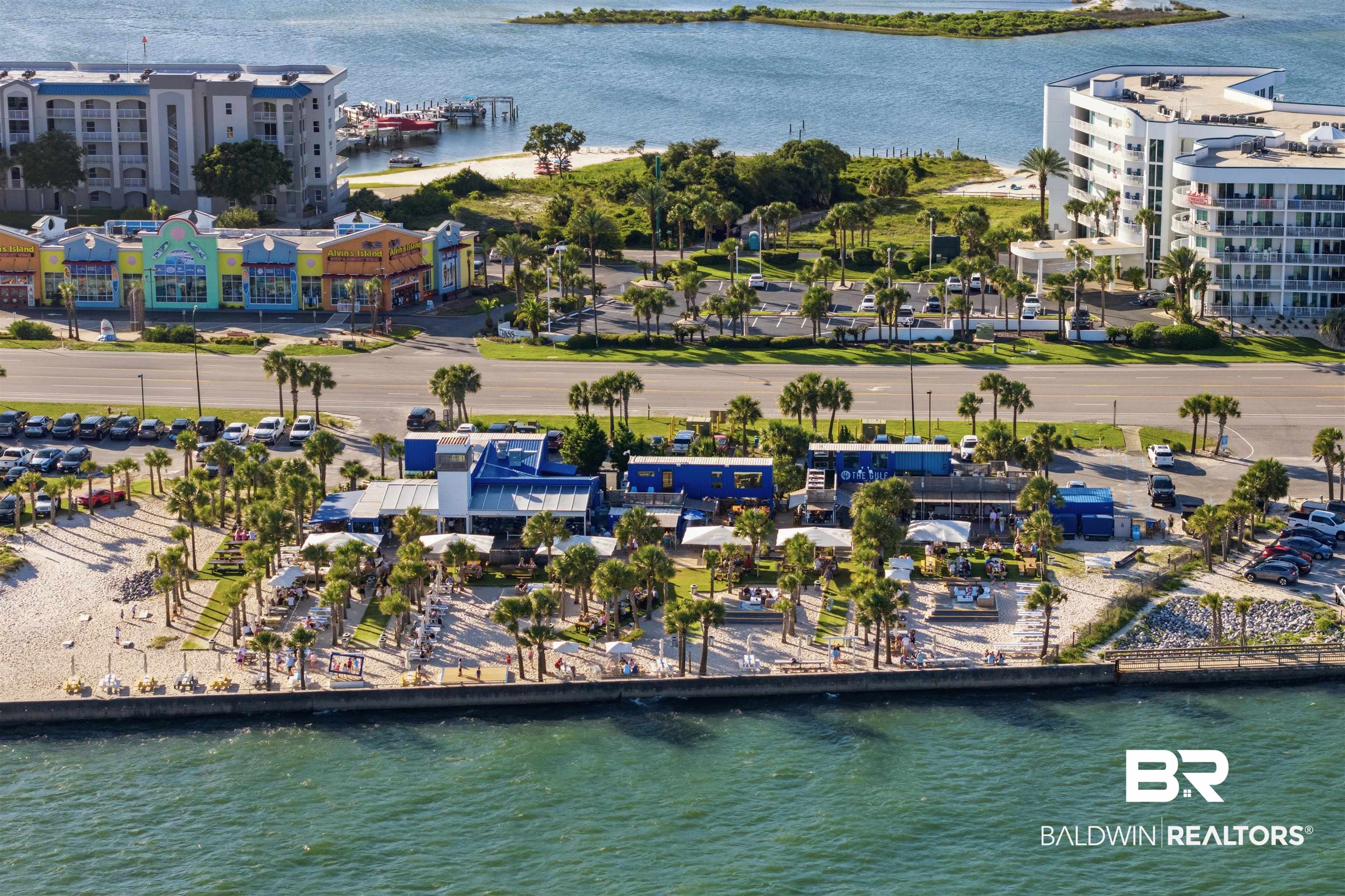 3564 Bayou Road, Unit 203 Orange Beach, AL 36561 - Photo 49 of 53 Waterfront area featuring a sandy shoreline with multiple seating areas, mature palm trees, and direct water access