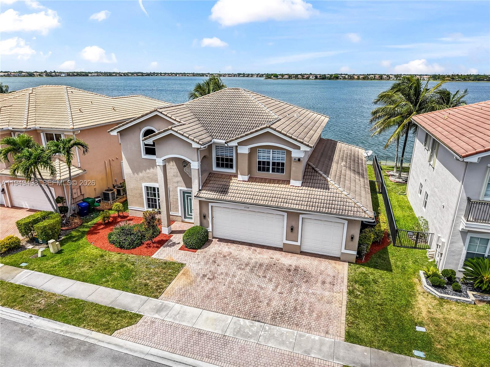 a front view of a house with a garden and lake view