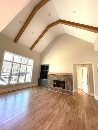 an empty room with wooden floor fireplace and windows