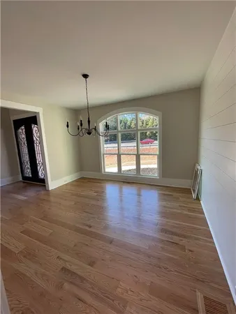 a view of an empty room with window and wooden floor