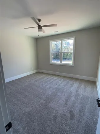an empty room with a ceiling fan and window