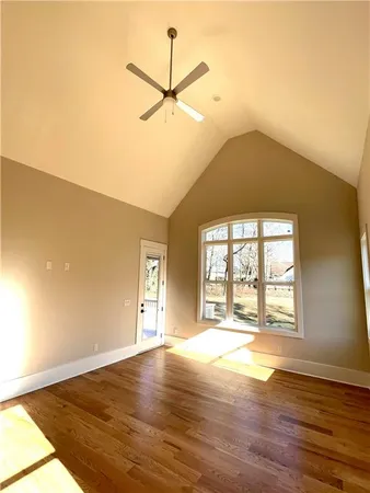 an empty room with wooden floor fan and windows