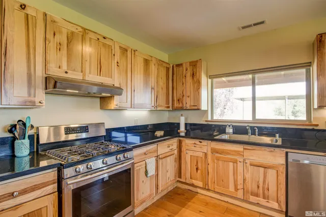 a kitchen with stainless steel appliances granite countertop a sink stove and cabinets
