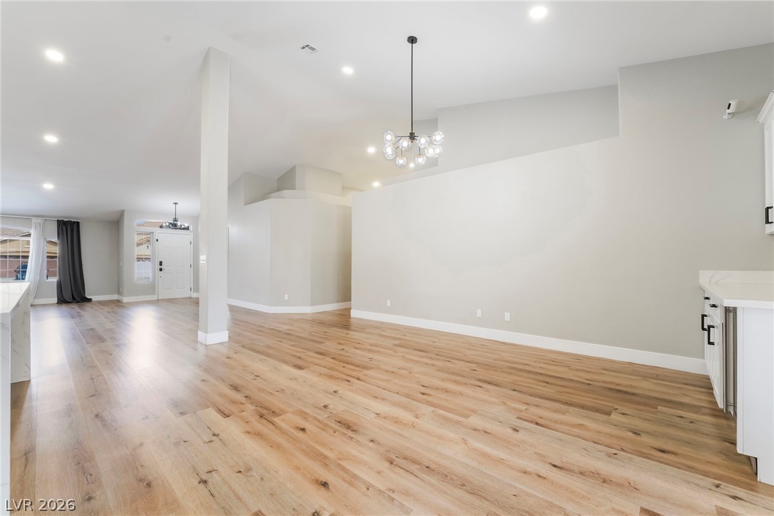 9171 West Viking Road Las Vegas, NV 89147 - Photo 13 of 43 Luminous hardwood floors flow through an inviting, open-concept living space, crowned by a captivating chandelier.