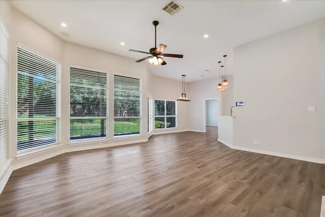 a view of an empty room with wooden floor and a window