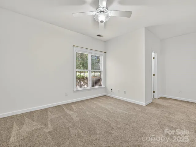an empty room with a chandelier fan and windows