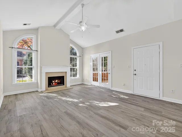 a view of an empty room with wooden floor fireplace and a window
