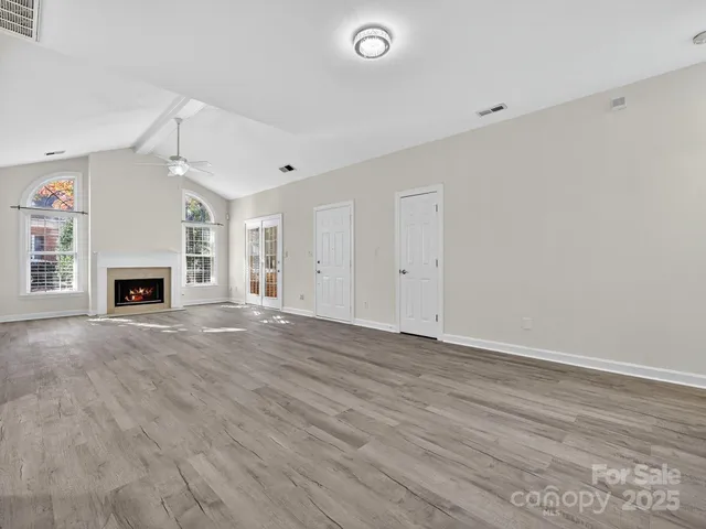 an empty room with wooden floor fireplace and windows