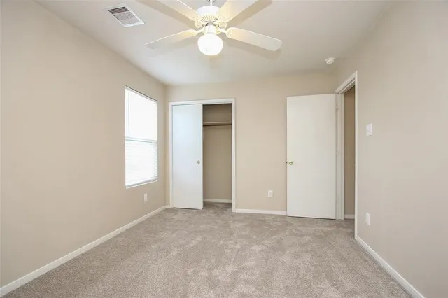 an empty room with windows and fan