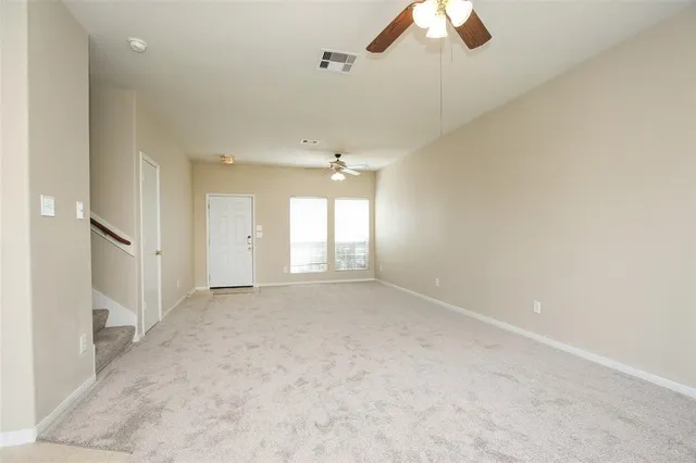 an empty room with a ceiling fan and window