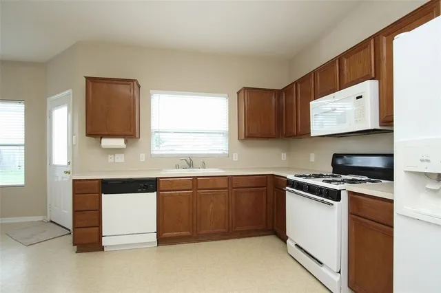 a kitchen with stainless steel appliances granite countertop a sink and a stove next to a window