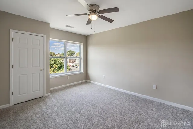 an empty room with windows and ceiling fan