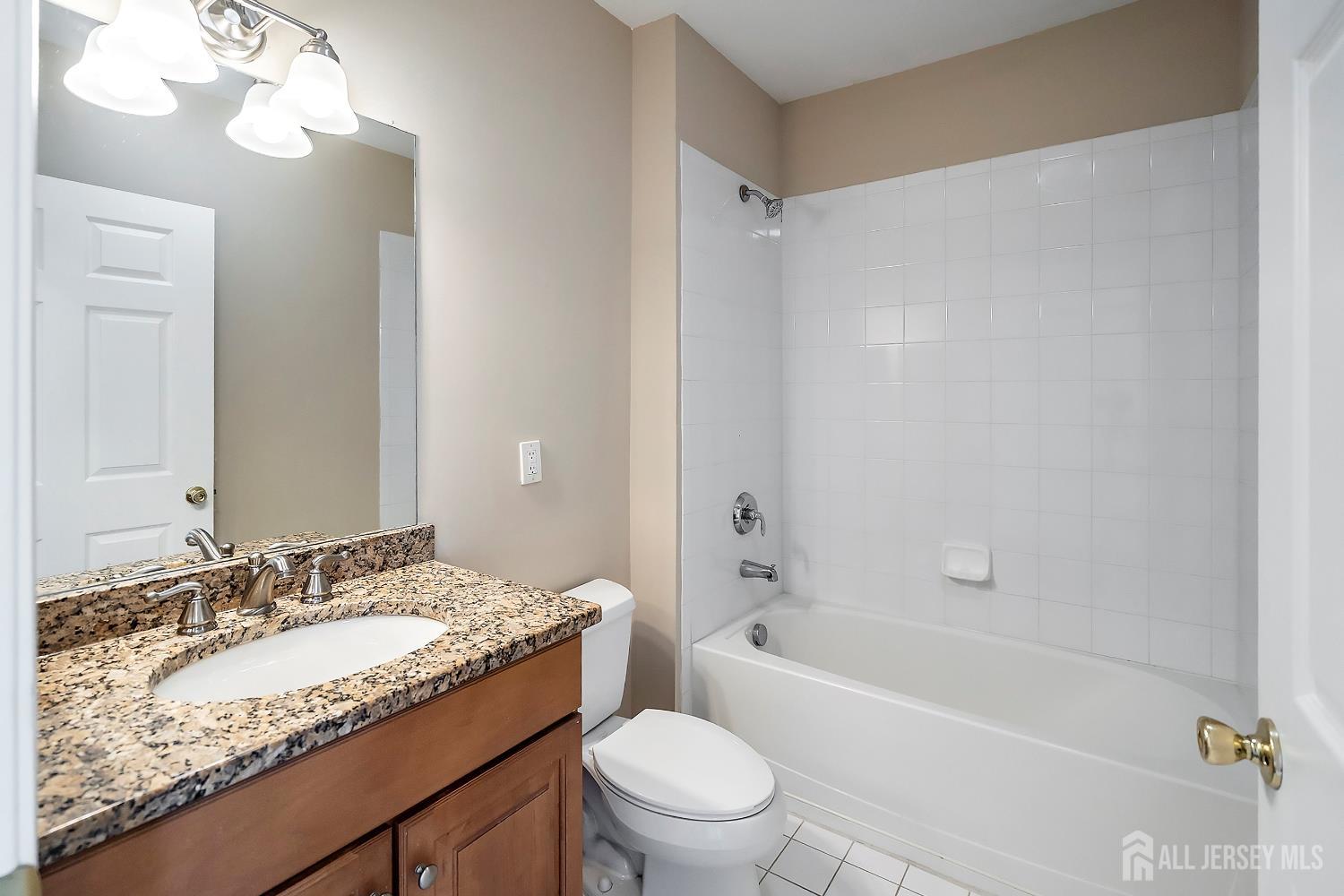 368 Rector Street, Unit 521 Perth Amboy, NJ 08861 - Photo 14 of 41 a bathroom with a granite countertop sink a mirror a toilet and bathtub