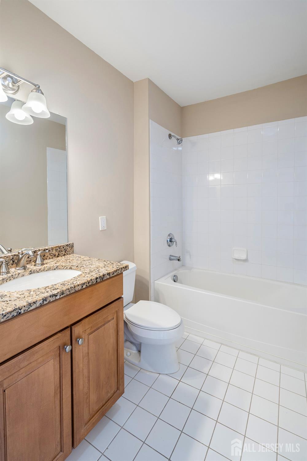 368 Rector Street, Unit 521 Perth Amboy, NJ 08861 - Photo 15 of 41 a bathroom with a granite countertop sink toilet mirror vanity and bathtub