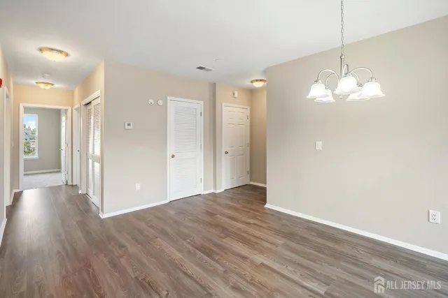 a view of a hallway with wooden floor and a chandelier
