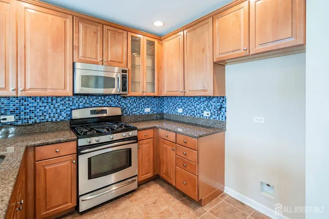 a kitchen with stainless steel appliances granite countertop a stove a sink and a microwave
