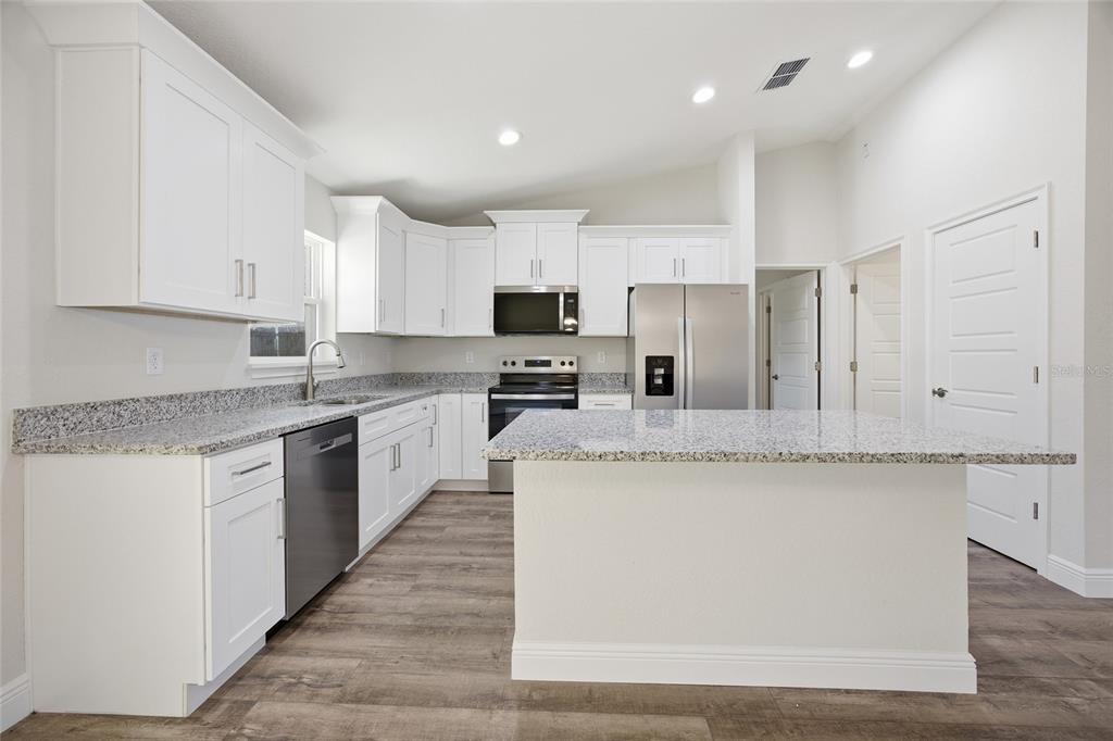 6762 Cherry Road Ocala, FL 34472 - Photo 7 of 29 a large kitchen with granite countertop a stove top oven a sink dishwasher and a refrigerator with wooden floor