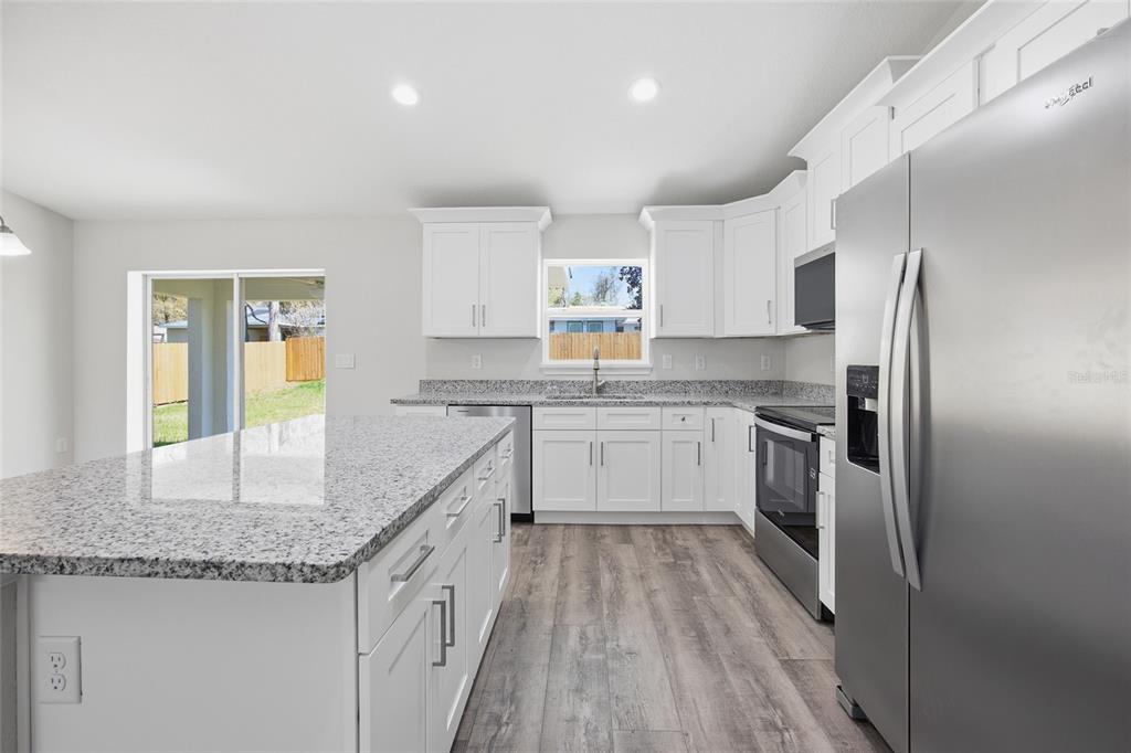 6762 Cherry Road Ocala, FL 34472 - Photo 8 of 29 a kitchen with granite countertop a sink stove refrigerator and cabinets