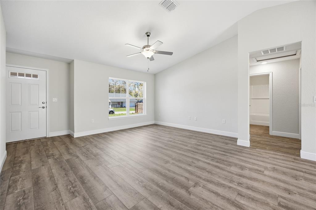 6762 Cherry Road Ocala, FL 34472 - Photo 9 of 29 an empty room with wooden floor chandelier fan and windows