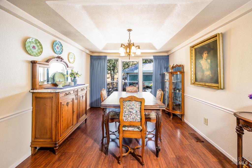 6707 Badger Creek Road Santa Rosa, CA 95409 - Photo 13 of 53 a dining room with wooden floor a chandelier a wooden table and chairs