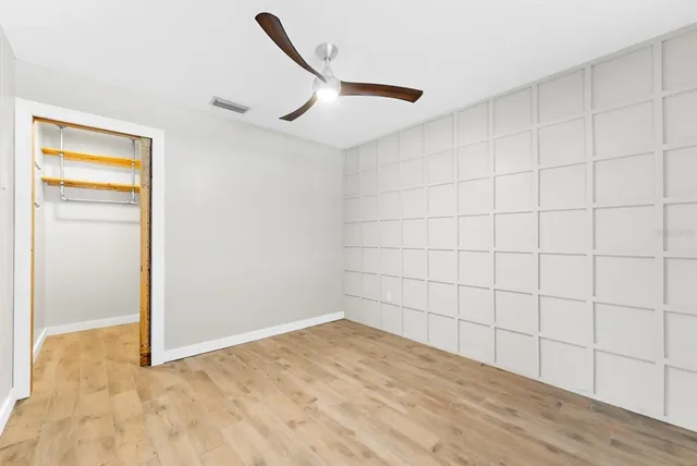 an empty room with wooden floor closet and windows