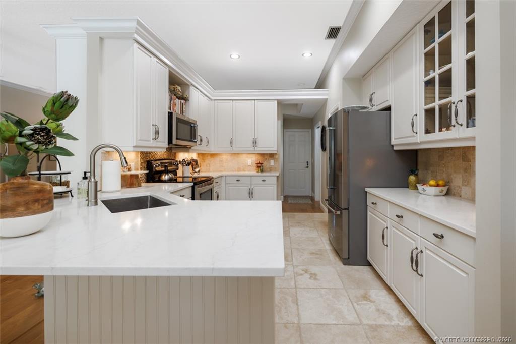1976 Southwest Oak Ridge Road Palm City, FL 34990 - Photo 16 of 65 a kitchen with stainless steel appliances a refrigerator sink and white cabinets
