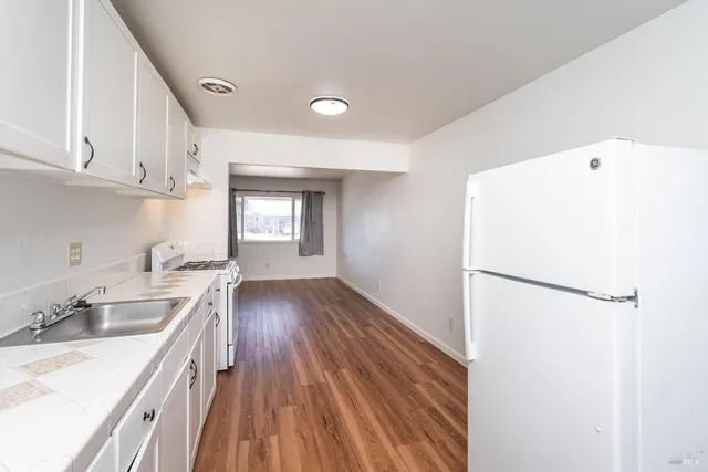 a kitchen with a sink a refrigerator and white cabinets