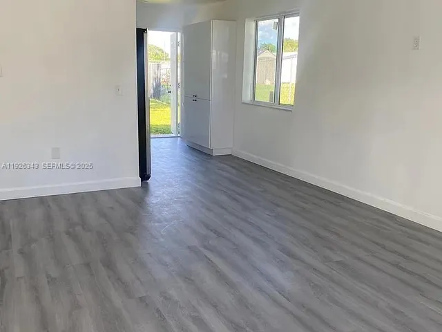 an empty room with wooden floor and window