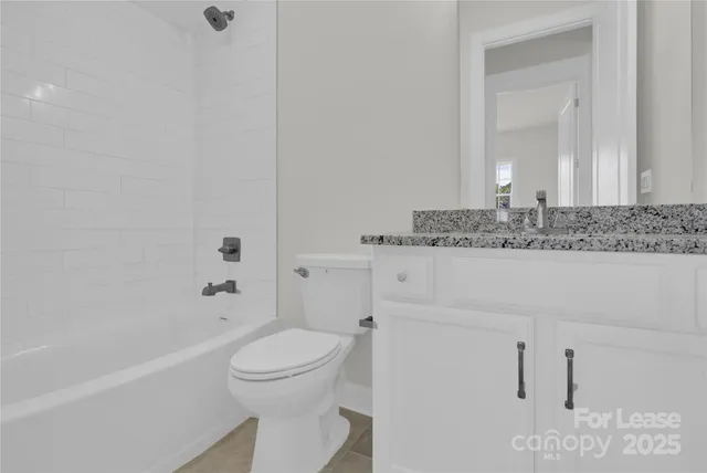 a bathroom with a granite countertop sink a toilet and bathtub