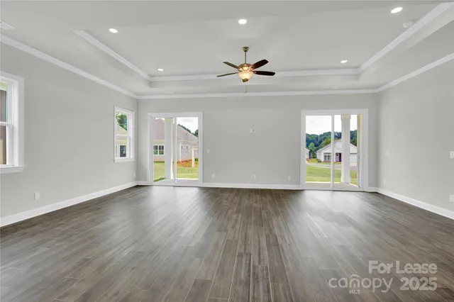 a view of an empty room with a window and wooden floor