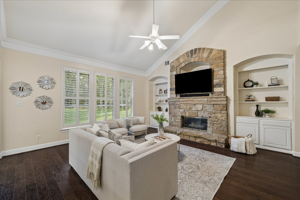 14530 Millhouse Road Pinehurst, TX 77362 - Photo 12 of 46 Another view of the living room centered around a stone fireplace, featuring built-in cabinetry and warm wood floors.