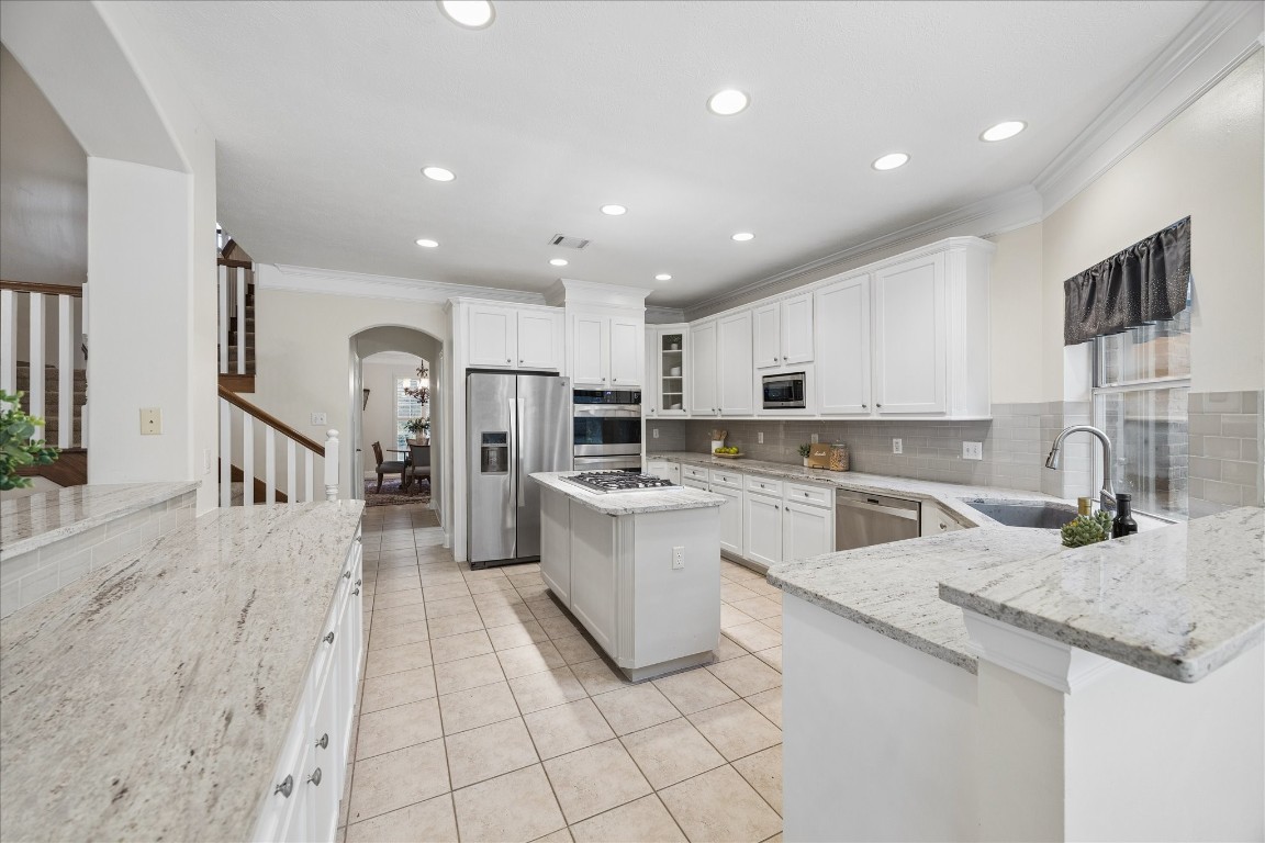 14530 Millhouse Road Pinehurst, TX 77362 - Photo 15 of 46 View from the breakfast area highlighting the kitchen’s U-shaped layout, extended counter space, recessed lighting, stainless steel appliances and connectivity to the main living areas.