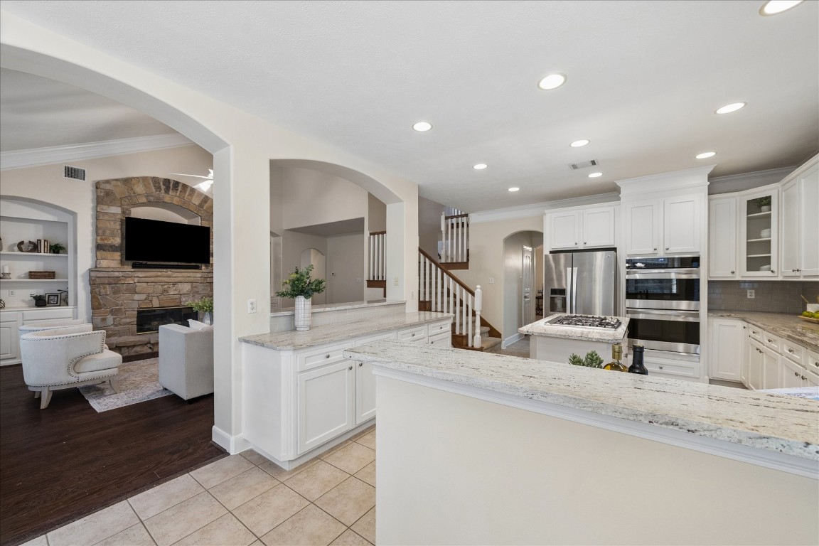 14530 Millhouse Road Pinehurst, TX 77362 - Photo 16 of 46 Another view of the kitchen highlighting the open-concept layout with sightlines to the living room and staircase, ideal for connected everyday living and entertaining.