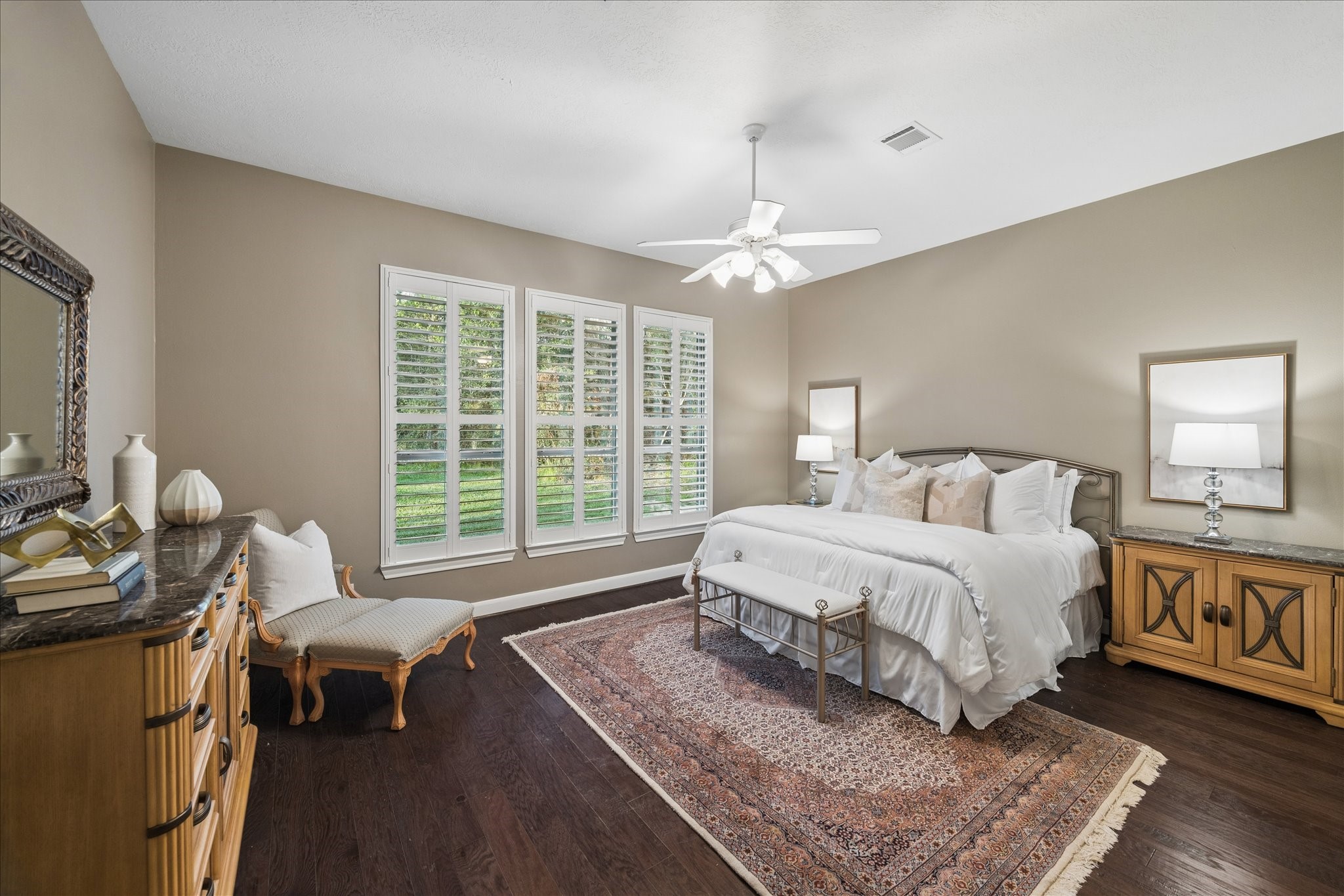 14530 Millhouse Road Pinehurst, TX 77362 - Photo 18 of 43 First-floor primary bedroom featuring wood flooring and multiple windows with plantation shutters, offering views of the backyard.