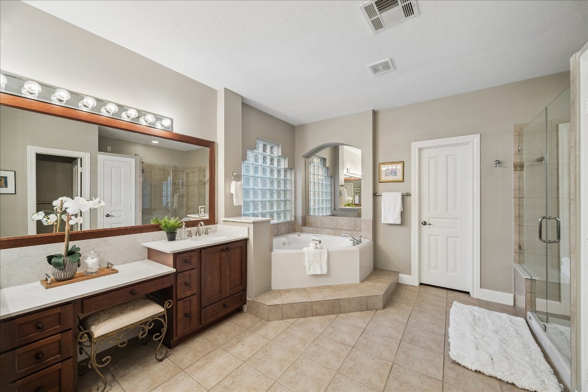 14530 Millhouse Road Pinehurst, TX 77362 - Photo 20 of 46 Primary bathroom with dual vanities, soaking tub, separate glass-enclosed shower, tile flooring, and updated finishes.