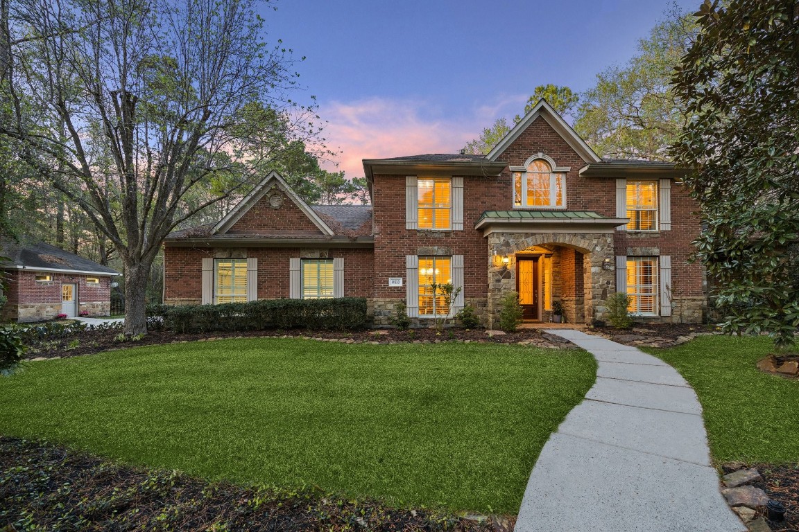 14530 Millhouse Road Pinehurst, TX 77362 - Photo 2 of 46 Front elevation framed by mature pines and landscaped beds, reflecting the home’s wooded setting and sense of privacy.