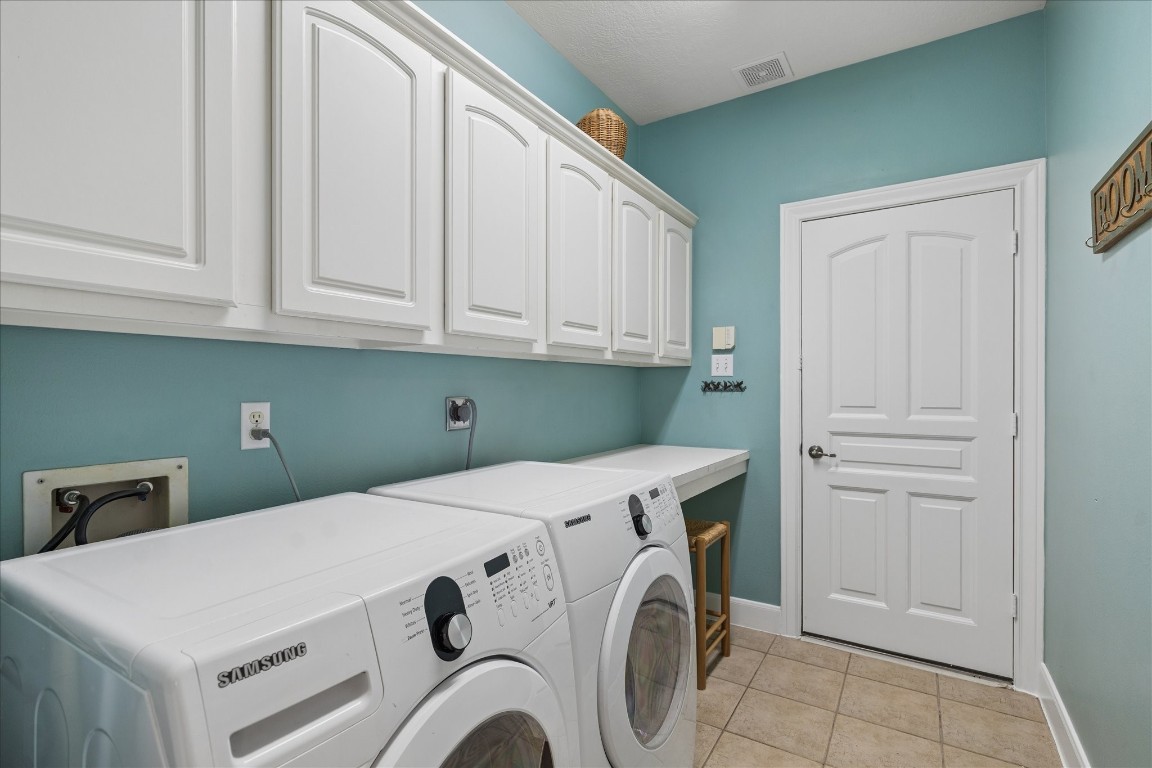 14530 Millhouse Road Pinehurst, TX 77362 - Photo 30 of 46 Dedicated utility room with upper cabinetry, folding space, and convenient access to the three-car garage, designed for everyday efficiency.