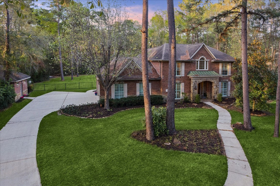 14530 Millhouse Road Pinehurst, TX 77362 - Photo 3 of 46 Expansive front grounds framed by mature pines and landscaped beds, with a winding walkway leading to the front entry and a wide driveway offering ample approach and parking.