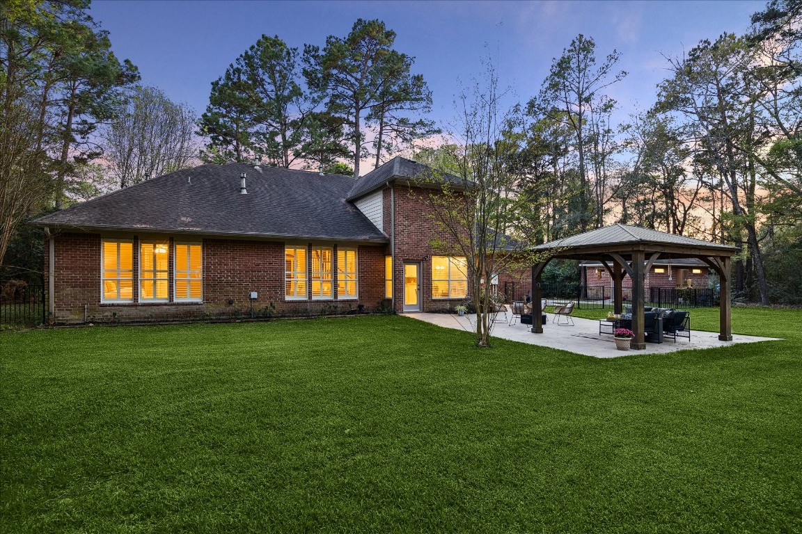 14530 Millhouse Road Pinehurst, TX 77362 - Photo 33 of 46 Rear elevation showcasing a spacious backyard with mature trees and extended patio, creating a seamless connection to outdoor living areas.