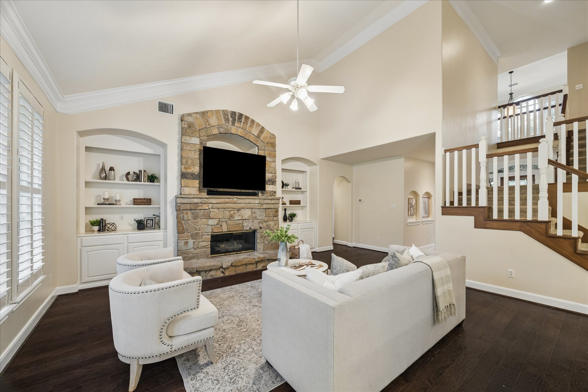 14530 Millhouse Road Pinehurst, TX 77362 - Photo 9 of 43 Living room with high ceilings, wood flooring, built-in shelving, and a stone fireplace with raised hearth and arched surround as focal point.