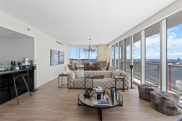 a living room with furniture large window and wooden floor